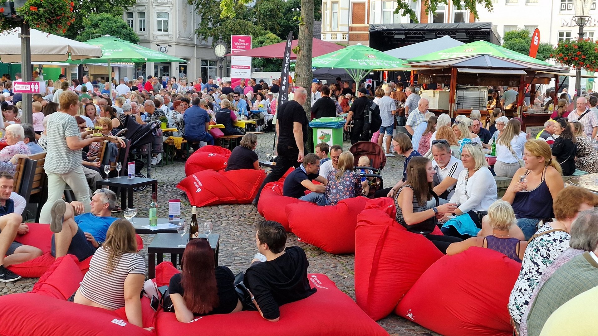 Das Bild zeigt viele Menschen, die es sich auf dem Marktplatz in Peine beim Weinfest gemütlicht machen. 