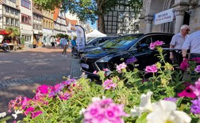 Das Bild zeigt mehrere Autos, die in der Innenstadt von Peine ausgestellt sind. Im Vordergrund befinden sich Blumenarrangement. 