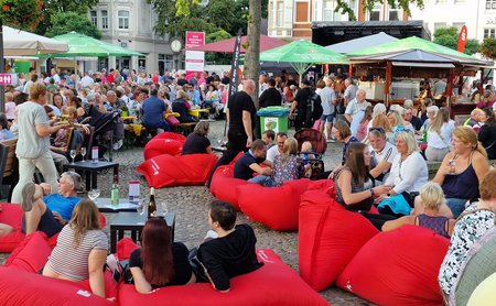 Das Bild zeigt viele Menschen, die es sich auf dem Marktplatz in Peine beim Weinfest gemütlicht machen. 