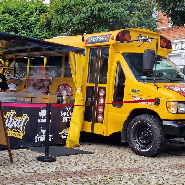 Gelber Streetfood-Truck beim Food Truck Festival in Peine mit frisch zubereiteten Burgern – darunter Wagyu Beef und Krokodil-Burger – direkt auf dem Marktplatz serviert.