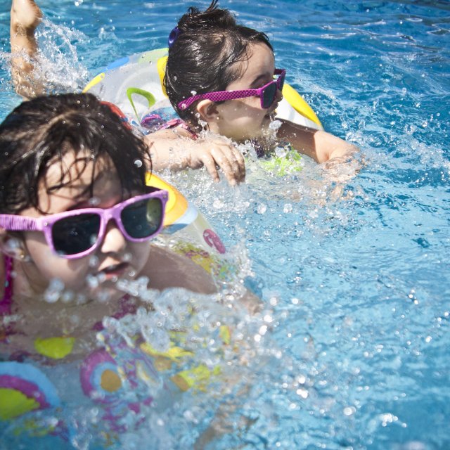 Das Bild zeigt zwei Kinder, die in einem Schwimmreifen stecken und im Freibad Peine baden gehen. 