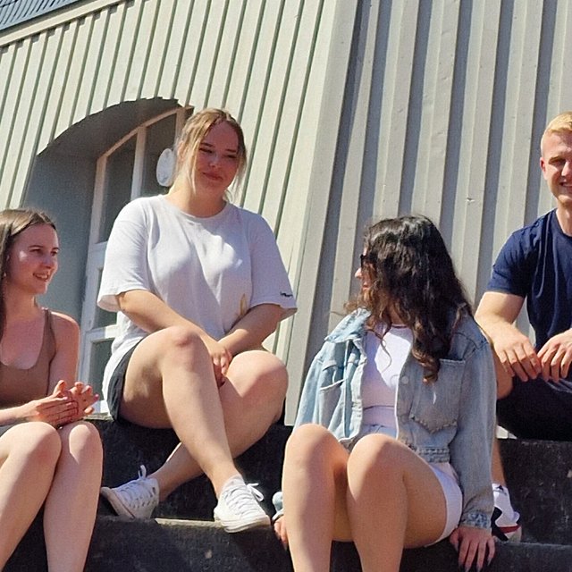 Das Bild zeigt eine Gruppe junger Menschen, die auf den Stufen vor der Töpfers Mühle in Peine sitzen. 