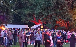 Das Bild zeigt tanzende Menschen im Burgpark in Peine im Discolicht bei der Silent Music Party in Peine. 