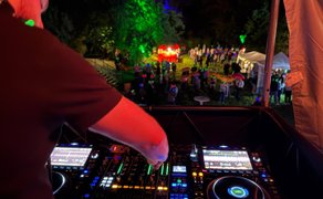 DJ steht an seinem Mischpult und legt bei der Silent Music Party Peine vor Gästen mit Kopfhörern auf.