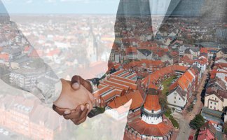 Das Bild zeigt eine Luftaufnahme von Peine darüber sind zwei Personen, die sich die Hand reichen. 