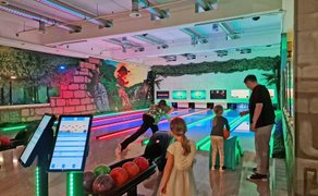 Das Bild zeigt Menschen, die auf einer Bowlingbahn spielen.