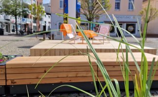 Open Stage in der Peiner Innenstadt mit Holzplattform, Sitzgelegenheiten und Begrünung als offener Treffpunkt für Kultur, Begegnung und urbanes Stadtleben.