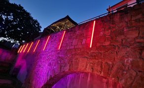 Das Bild zeigt die mit Discolicht leuchtete Mauer im Burgpark in Peine. 