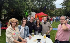  Fünf Personen mit Funkkopfhörern stehen lächelnd an einem Stehtisch.
