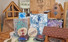 Holzarbeiten in verschiedenen Formen und Farben, darunter Vogelhäuser und ein Flaschenträger. 