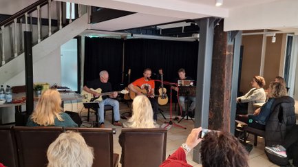 Das Bild zeigt eine Gruppe Musiker im Peiner Schwan. Davor sitzt das Publikum mit dem Rücken zum Fotografen gewandt. 