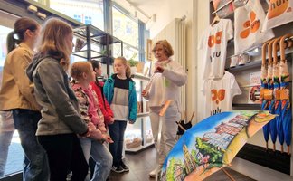 Schülerinnen lassen sich in der Tourist-Information von Peine Marketing das Sortiment des Shops zeigen.