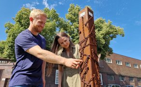 Zwei Teilnehmende lösen gemeinsam ein Rätsel an einer Station der digitalen Stadtrallye in Peine im Außenbereich.