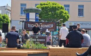 DJ-Auftritt bei der Open Stage auf dem Marktplatz in Peine mit Techno-Bunker-Bühne, sitzendem Publikum auf Holzbänken und sommerlicher Atmosphäre in der Innenstadt.