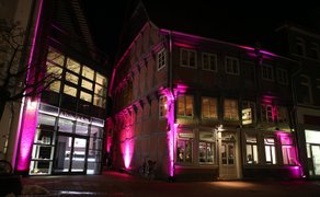 Das Bild zeigt den historischen Schwan in Peine, das älteste Gebäude der Stadt, in der Nacht in pink beleuchtet. 