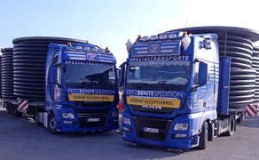 Zwei blaue Sattelzugmaschinen der Firma Fritz Bente Spedition mit großen Kabeltrommeln auf den Aufliegern.