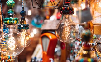 Detailaufnahme von kunsthandwerklichen Lampen mit dekorativen Glühbirnen: Handgefertigte Leuchten aus Glas, Metall und bunten Perlen leuchten warm und schaffen eine gemütliche Atmosphäre auf einem Kunsthandwerkermarkt in Peine.