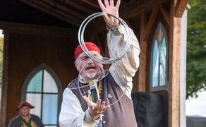Besucher verfolgen die Gauklershow beim Winterzauber in Peine mit artistischer Ringkunst auf der Bühne im Burgpark.