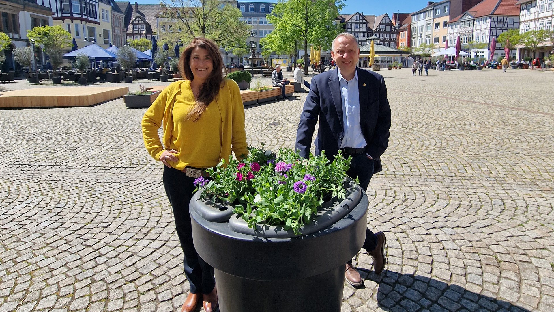 Das Bild zeigt die Geschäftsführerin der Peine Marketing GmbH, Anja Barlen-Herbig, und Peines Bürgermeister Klaus Saemann vor einem neuen Blumenpod in der Peiner Innenstadt. 