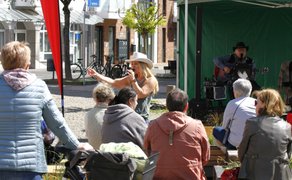 Sängerin mit Cowboyhut singt und interagiert mit dem Publikum auf der Open Stage in Peine, im Hintergrund Gitarrist auf kleiner Bühne am Marktplatz.