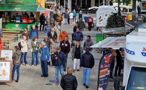 Besucherinnen und Besucher schlendern zwischen mehreren Foodtrucks und Getränkeständen auf dem Streetfood-Festival in Peine, mit Warteschlangen, Sitzbänken und lebendiger Marktatmosphäre.