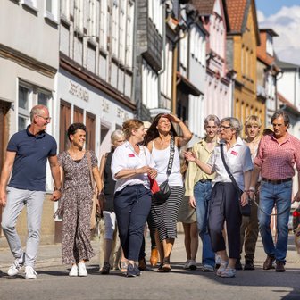 Das Bild zeigt eine Gruppe Menschen, die eine Stadtführung in Peine machen, und sich gerade am Damm befinden. 