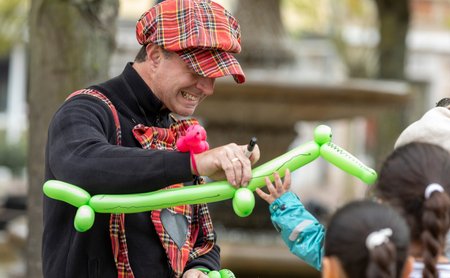 Das Bild zeigt einen Künstler, der aus Luftballons Gummitierchen bastelt. 