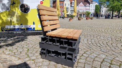 Das Bild zeigt einen Holzsessel auf dem Historischen Marktplatz in Peine, was als Kunst im öffentlichen Raum gilt. 