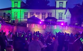 Das Bild zeigt tanzende Menschen im Burgpark in Peine im Discolicht bei der Silent Music Party in Peine. 