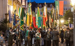 Festumzug beim Peiner Freischießen am Abend, mit Schützen in traditioneller Uniform, Fahnenabordnungen und beleuchteter Innenstadt.
