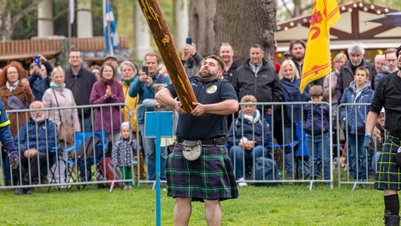 Mann in Kilt wirft schweren Holzstamm beim Highland Gathering vor Publikum im Peiner Stadtpark