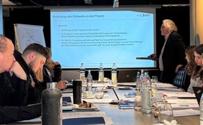 Geschäftliches Seminar im Tagungsraum in Peine: Teilnehmende sitzen an einem Konferenztisch, während ein Referent eine Präsentation mit Folien zu Einkaufs- und Vergabeprozessen hält; ideal für Meetings, Workshops und Fortbildungen.