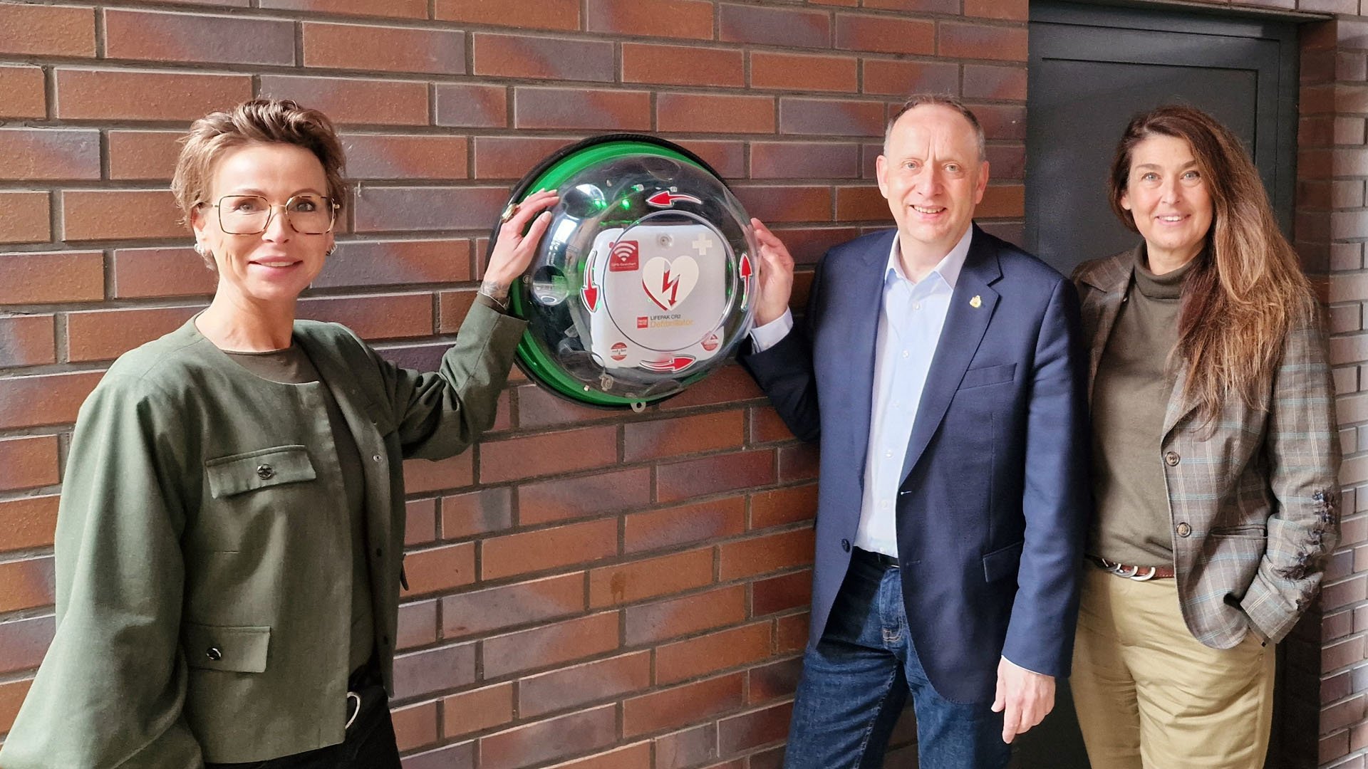 Von links nach rechts: Nela Bode-Beck (Geschäftsführerin des ASB Kreisverbandes Peine), Klaus Saemann (Bürgermeister und Aufsichtsratsvorsitzender Peine Marketing) und Anja Barlen-Herbig (Geschäftsführerin Peine Marketing) zeigen den lebensrettenden Defibrillator im Hof der Geschäftsstelle von Peine Marketing. 