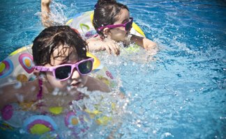 Das Bild zeigt zwei Kinder, die in einem Schwimmreifen stecken und im Freibad Peine baden gehen. 
