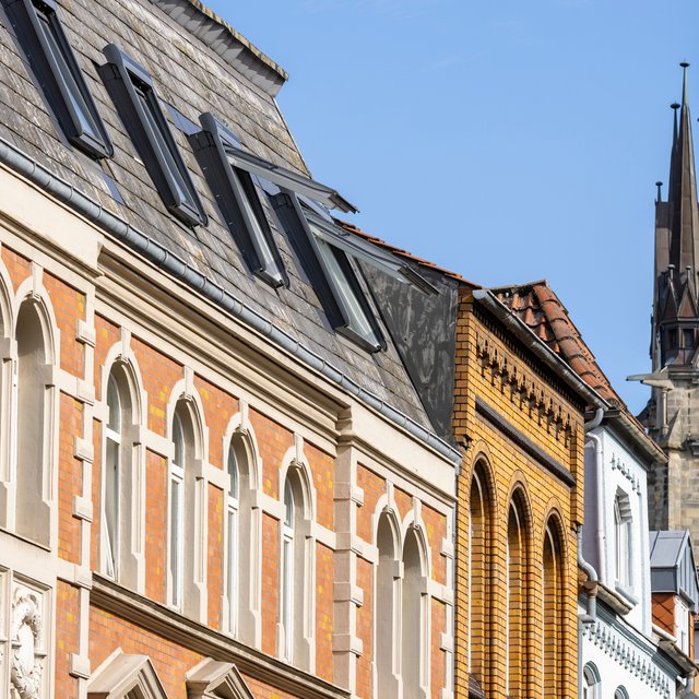 Das Bild zeigt eine historische Häuserzeile in der Peiner Innenstadt mit dem Kirchturm der St. Jakobi Kirche im Hintergrund. 