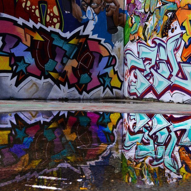 Das Bild zeigt eine Wand, die mit Grafitties besprüht ist.