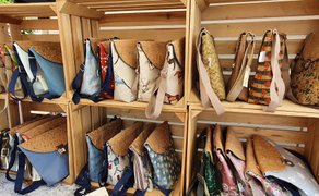 Regal aus Holzkisten mit handgefertigten Taschen aus Korkmaterial in verschiedenen Formen und Mustern.