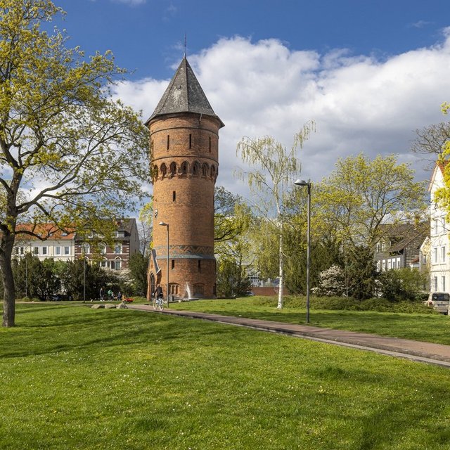 Wasserturm am Friedrich-Ebert-Platz in Peine mit grüner Parkanlage und blauem Himmel – beliebtes Wahrzeichen der Stadt Peine.