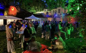 Gäste mit leuchtenden Kopfhörern feiern und unterhalten sich bei der Silent Music Party Peine vor beleuchteten Gebäuden.