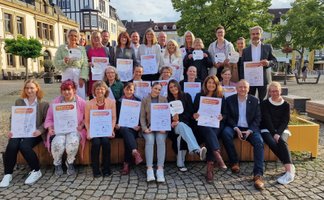 Gruppenfoto zur Verleihung des Peiner Gütesiegels: Ausgezeichnete Betriebe präsentieren ihre Zertifikate auf dem Historischen Marktplatz in Peine.