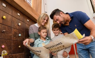 Familie mit zwei Kindern liest gemeinsam eine Karte bei der Museumsschatzsuche im Kreismuseum Peine.