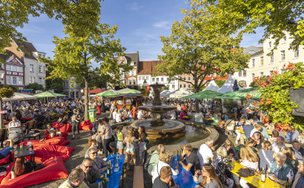 Besucher genießen das Weinfest auf dem historischen Marktplatz in Peine mit Brunnen, Fachwerkhäusern und sommerlicher Atmosphäre.