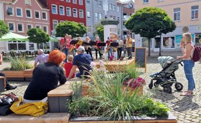 Das Bild zeigt das Publikum, das vor der OpenStage auf der Stadtoase auf dem Historischen Marktplatz in Peine Platz genommen hat. 