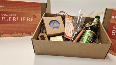 Geschenkbox „Bierliebe“ aus Peine mit einer Flasche Härke Pils, Bierglas, kleinen regionalen Produkten und dekorativer Verpackung auf einem Tisch.