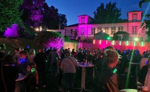 Das Bild zeigt tanzende Menschen im Burgpark in Peine im Discolicht bei der Silent Music Party in Peine. 