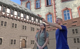 Zwei Personen stehen vor einer per Augmented Reality rekonstruierten historischen Burganlage und betrachten die digitale Darstellung der Peiner Burg.