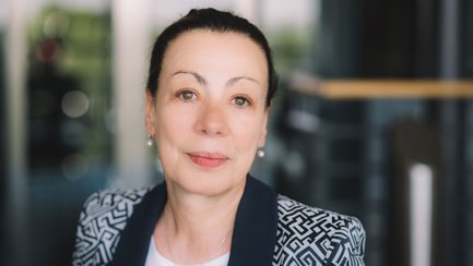 Das Bild zeigt das Porträt einer Frau vor einem unscharfem Hintergrund.