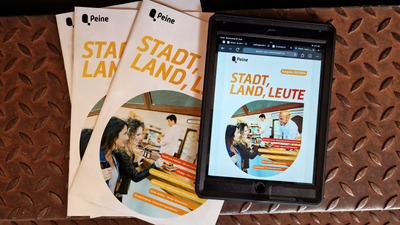 DAs Bild zeigt ein Tablet mit dem Stadtmagazin Stadt, Land, Leute darauf. Daneben liegen einige gedruckte Exemplare. 