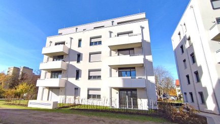 Mehrstöckiges modernes Wohngebäude mit Balkonen und großen Fenstern unter blauem Himmel