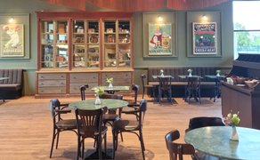 Das Café im Rausch Schokoladenhaus Peine zeigt einen stilvoll eingerichteten Gastraum mit gedeckten Tischen, Sitzbänken und historischen Schokoladenplakaten an den Wänden. Die ruhige Atmosphäre steht für Genuss in Peine und lädt zum Verweilen bei Schokolade, Kaffee und Konditorei-Spezialitäten ein.